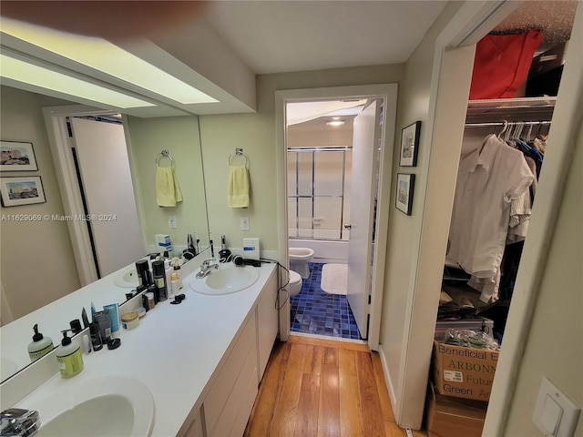 full bathroom with wood-type flooring, combined bath / shower with glass door, toilet, and vanity