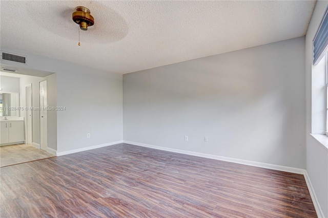 empty room with ceiling fan, hardwood / wood-style floors, and a textured ceiling