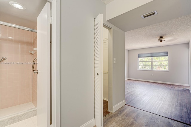 bathroom featuring hardwood / wood-style flooring, a textured ceiling, and tiled shower