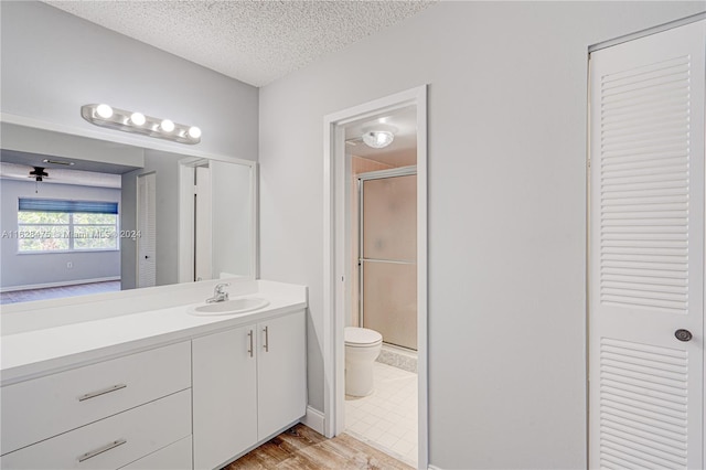 bathroom featuring toilet, tile patterned flooring, vanity, a textured ceiling, and a shower with shower door