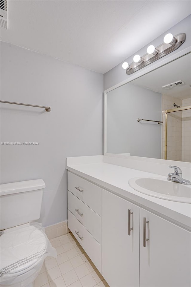 bathroom featuring toilet, vanity, tiled shower, and tile patterned floors