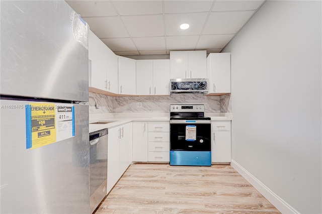 kitchen with a drop ceiling, light wood-type flooring, backsplash, and stainless steel appliances