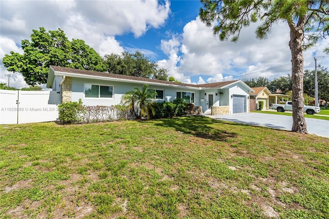 ranch-style home featuring a front lawn, fence, stucco siding, driveway, and an attached garage