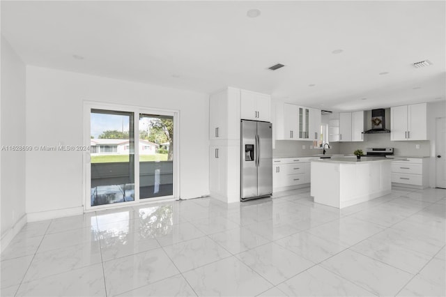 kitchen with appliances with stainless steel finishes, white cabinetry, sink, wall chimney range hood, and a kitchen island