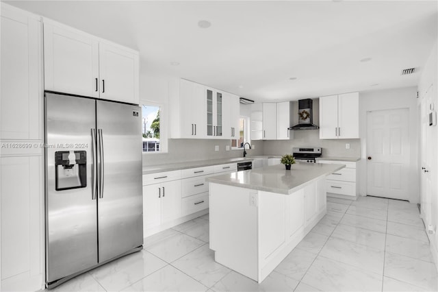 kitchen featuring a center island, appliances with stainless steel finishes, white cabinetry, and wall chimney exhaust hood