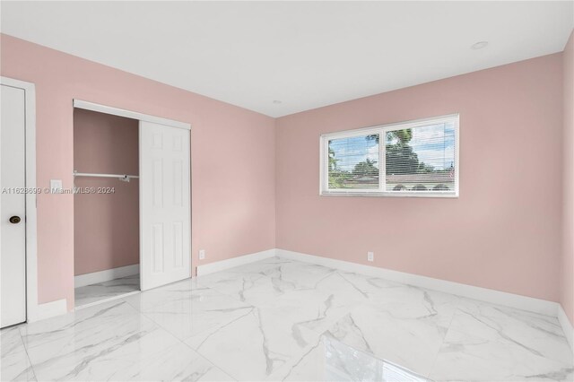 551 NW 42nd Ave, Coconut Creek, FL 33066 - unfurnished bedroom featuring a closet, baseboards, and marble finish floor
