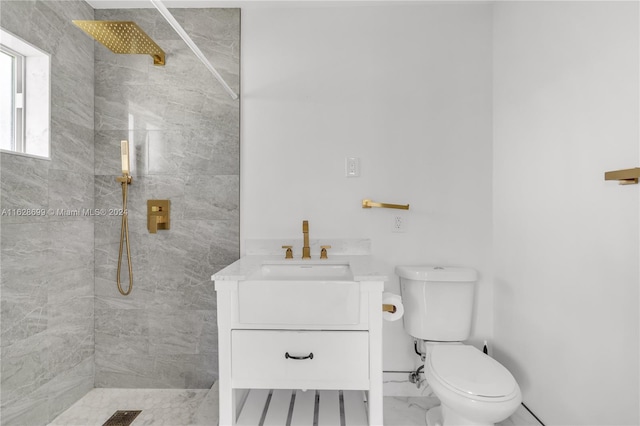 bathroom with vanity, toilet, and a tile shower