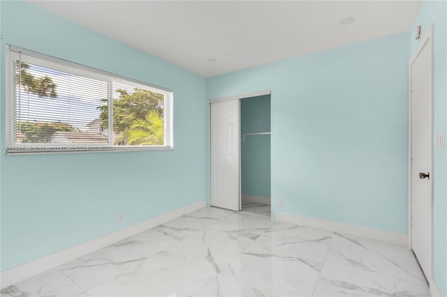 551 NW 42nd Ave, Coconut Creek, FL 33066 - unfurnished bedroom featuring a closet, baseboards, and marble finish floor