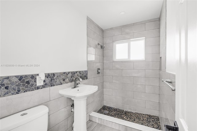 bathroom featuring tile walls, toilet, and a tile shower