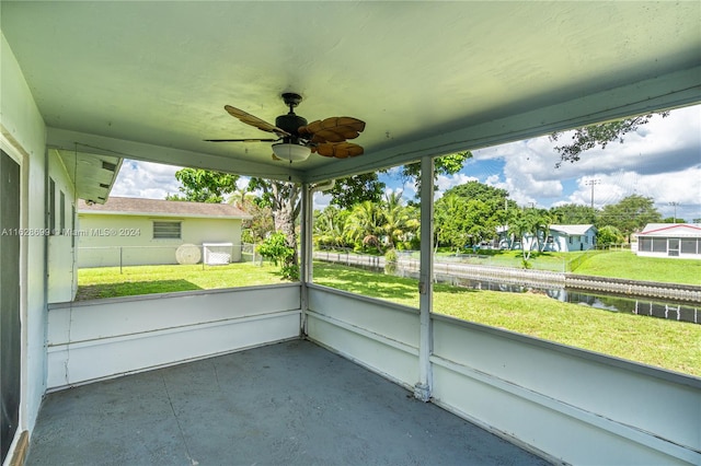 unfurnished sunroom with ceiling fan and a water view