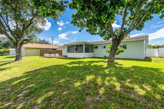 551 NW 42nd Ave, Coconut Creek, FL 33066 - back of house with a yard, a fenced backyard, and a sunroom