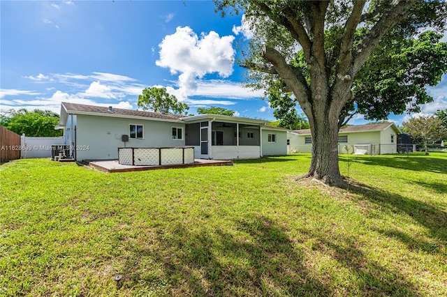 551 NW 42nd Ave, Coconut Creek, FL 33066 - rear view of house with a wooden deck, a yard, a fenced backyard, central AC, and a sunroom