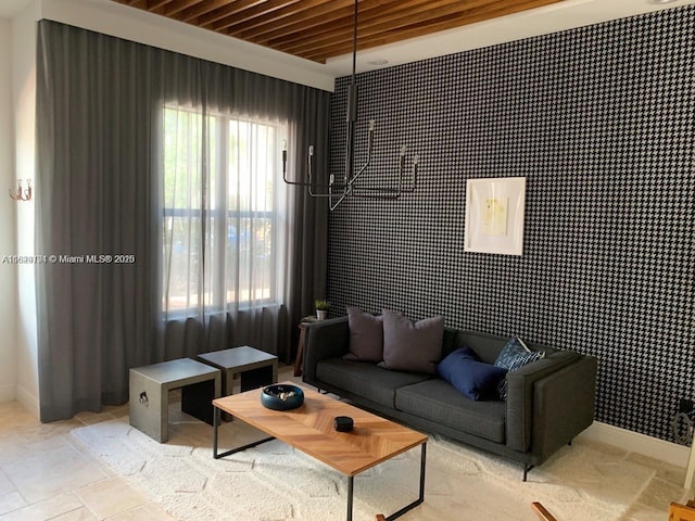 living room featuring an accent wall, wallpapered walls, and baseboards