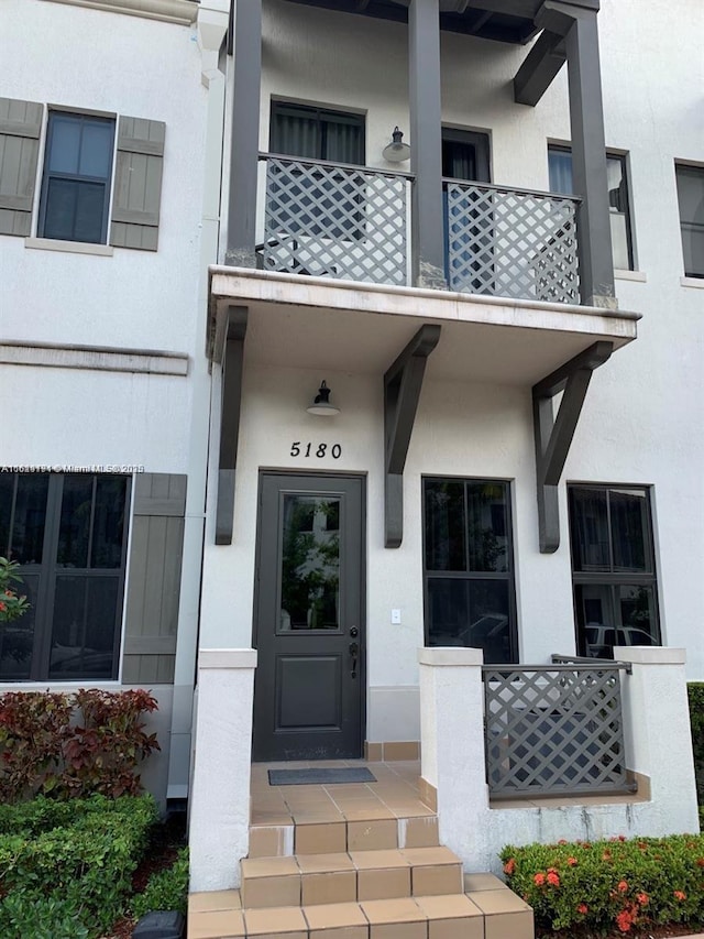 doorway to property with a balcony and stucco siding