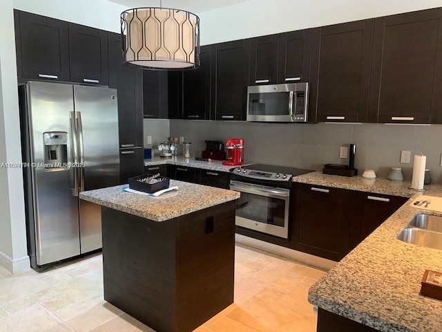 kitchen with stainless steel appliances, a center island, pendant lighting, and tasteful backsplash