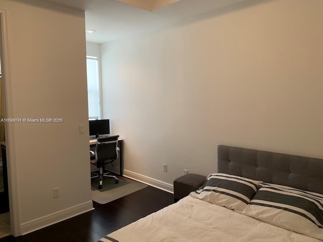 bedroom with dark wood-type flooring and baseboards