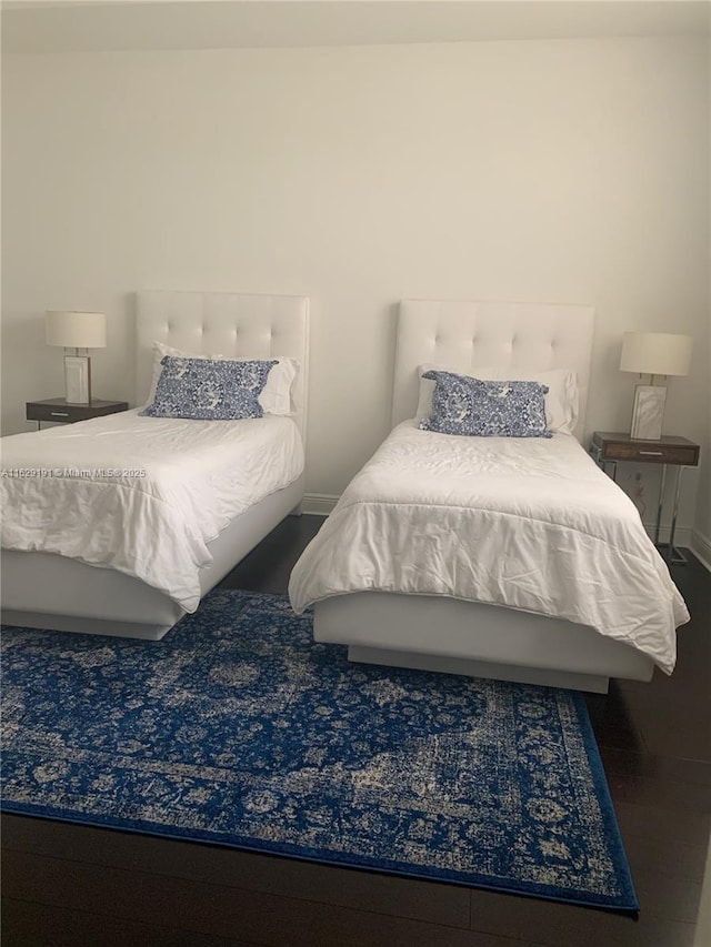 bedroom with baseboards and dark wood-type flooring