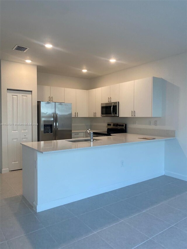 kitchen featuring white cabinets, tile patterned flooring, appliances with stainless steel finishes, and sink