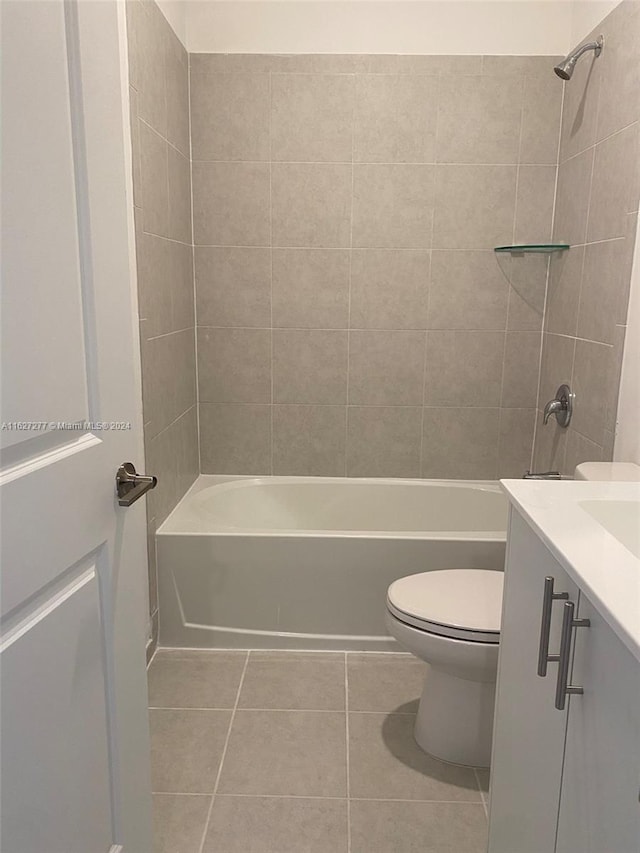 full bathroom with tile patterned flooring, vanity, tiled shower / bath combo, and toilet