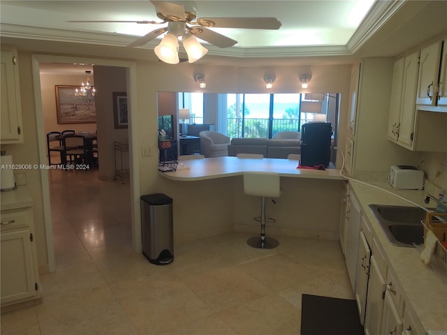 kitchen with sink, ceiling fan with notable chandelier, light tile patterned floors, and white cabinetry