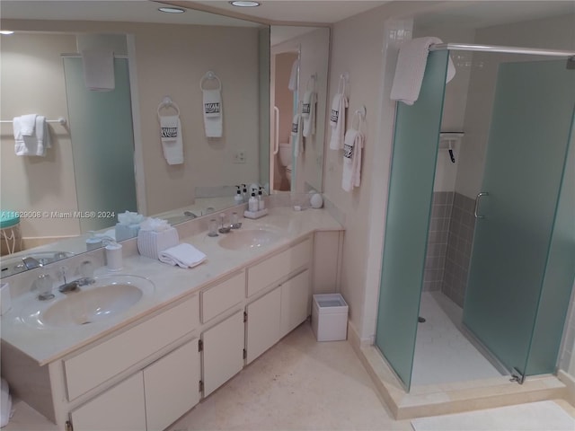 bathroom featuring a shower with shower door, double sink vanity, and tile patterned flooring