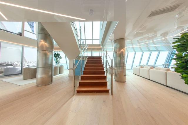 staircase with wood-type flooring and a towering ceiling