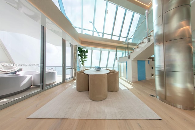 dining space with light wood-type flooring, a skylight, and a high ceiling