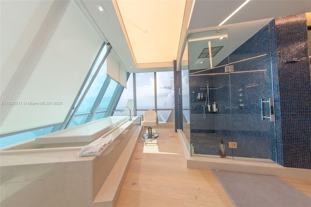 bathroom featuring wood-type flooring, a shower with door, and expansive windows