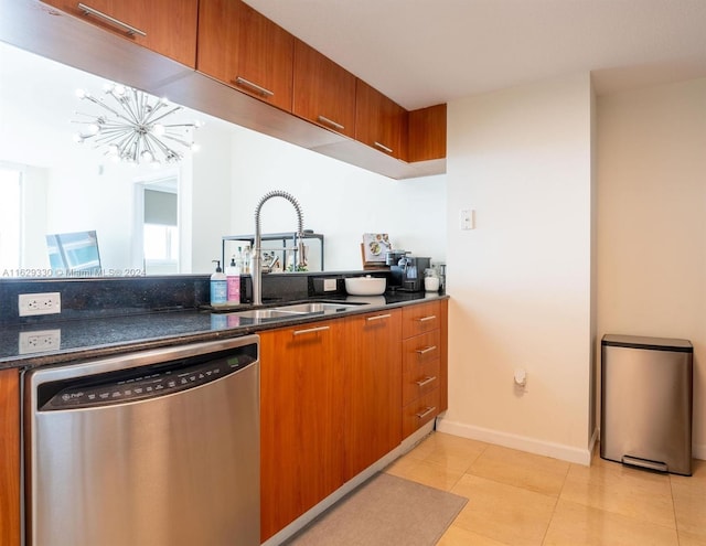 kitchen with sink, light tile patterned floors, stainless steel dishwasher, and dark stone counters