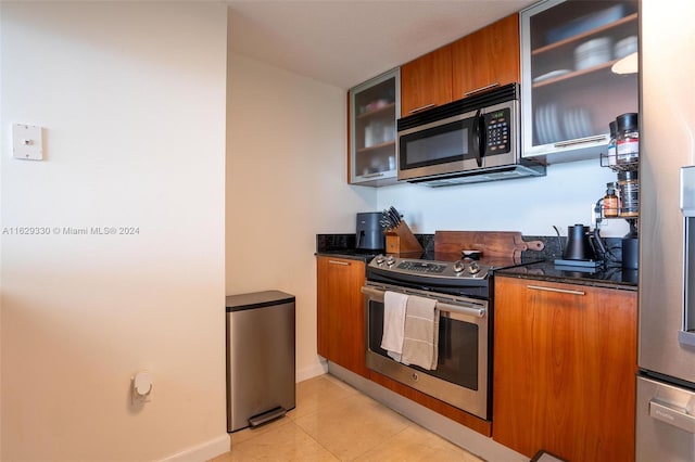 kitchen featuring dark stone countertops, light tile patterned flooring, and appliances with stainless steel finishes