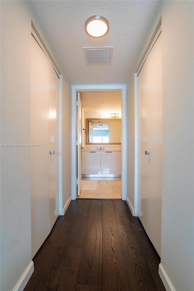 corridor featuring dark hardwood / wood-style flooring and a textured ceiling