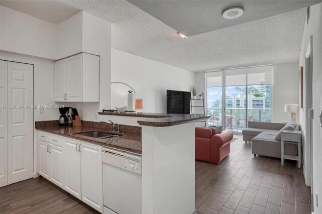 kitchen featuring dishwasher, dark hardwood / wood-style flooring, sink, kitchen peninsula, and a textured ceiling