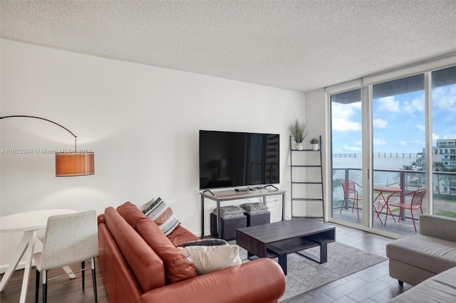 living room featuring a textured ceiling, light hardwood / wood-style flooring, and a wall of windows