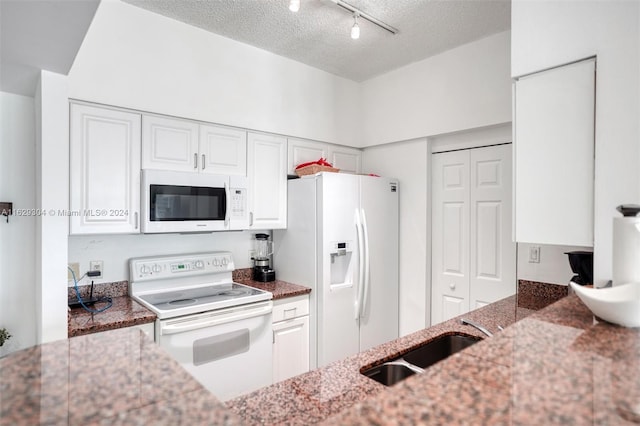 kitchen with a sink, stone countertops, white appliances, and white cabinets