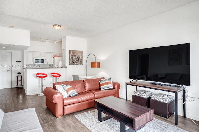 living room featuring track lighting, a textured ceiling, baseboards, and wood finished floors
