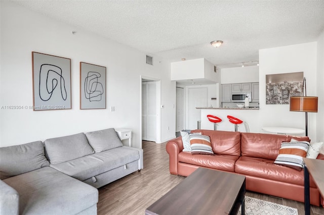 living area featuring visible vents, a textured ceiling, light wood-type flooring, and track lighting