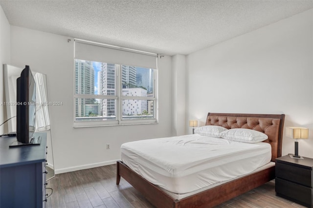 bedroom with dark hardwood / wood-style flooring and a textured ceiling