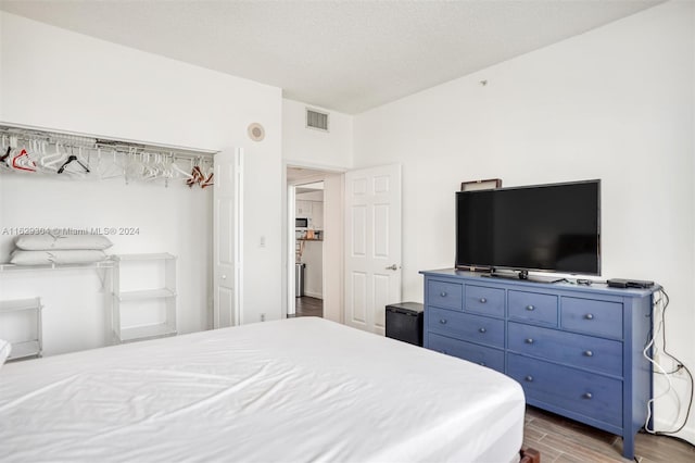 bedroom with wood finished floors, visible vents, and a textured ceiling