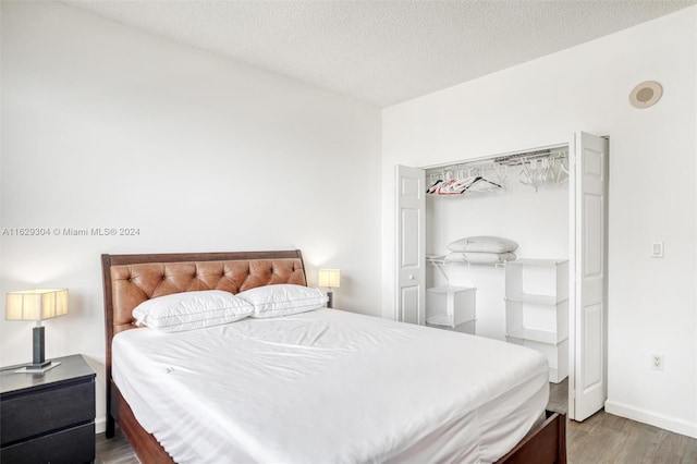 bedroom featuring wood finished floors, baseboards, and a textured ceiling