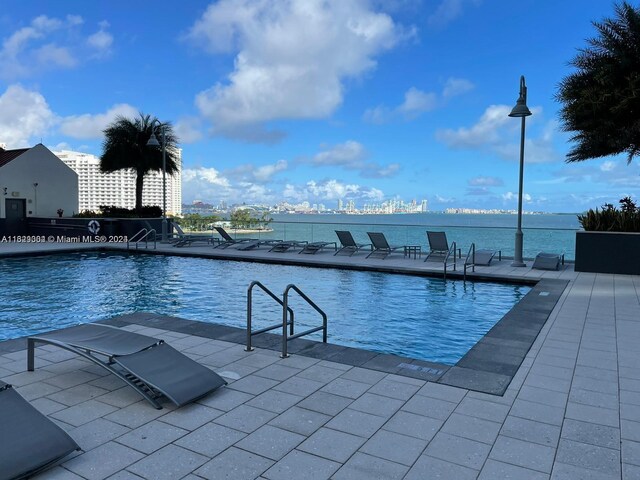 view of pool featuring a water view and a patio area