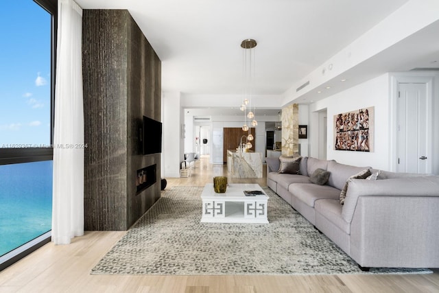 living room with a fireplace, a wall of windows, and light wood-type flooring