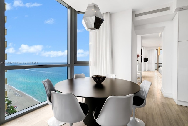 dining room with light hardwood / wood-style floors, floor to ceiling windows, and a water view