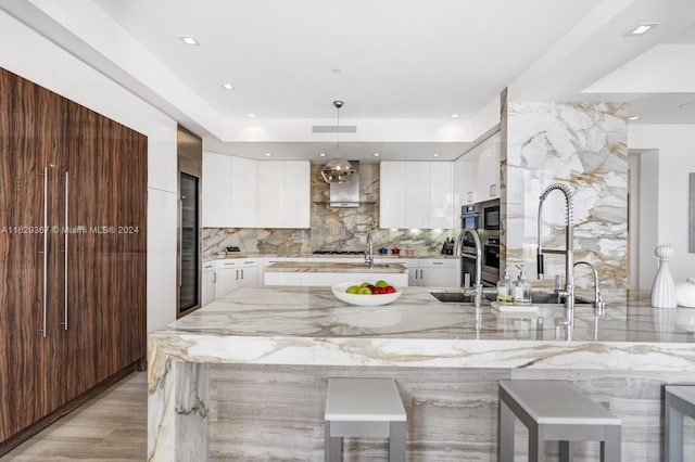 kitchen featuring white cabinets, tasteful backsplash, light wood-type flooring, and hanging light fixtures