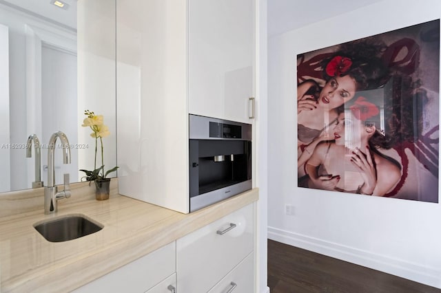 kitchen featuring hardwood / wood-style floors, stainless steel oven, sink, and white cabinets