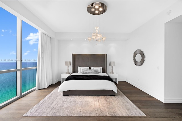 bedroom with a notable chandelier, dark hardwood / wood-style floors, and a water view