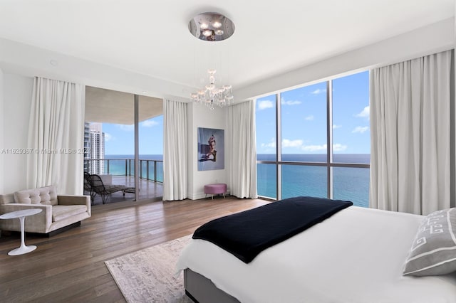 bedroom featuring hardwood / wood-style floors, access to outside, a chandelier, and a water view