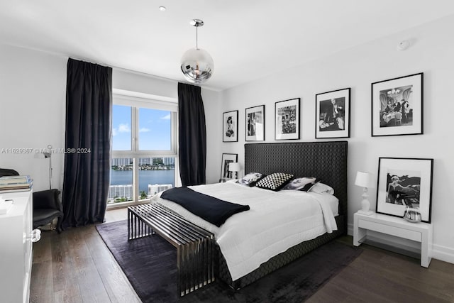 bedroom with hardwood / wood-style floors and a water view