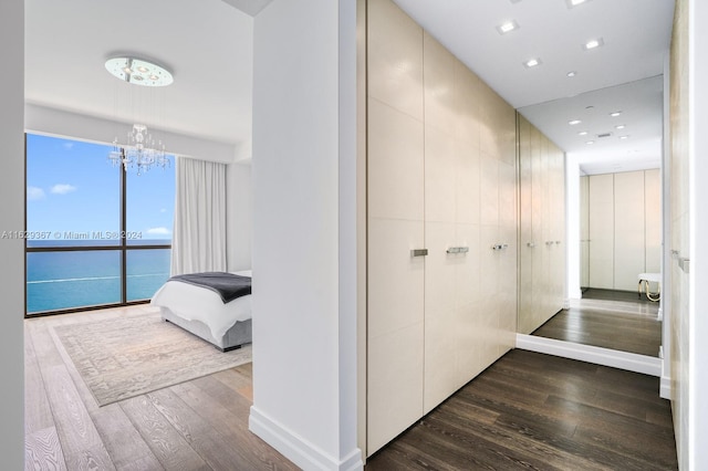 corridor with hardwood / wood-style flooring, a notable chandelier, floor to ceiling windows, and a water view