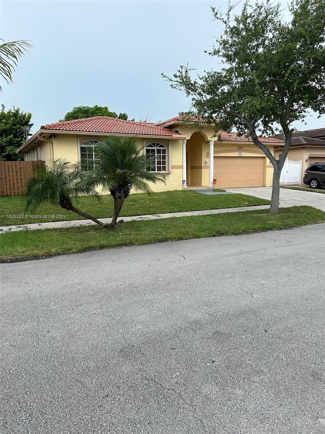 mediterranean / spanish home with a garage and a front lawn