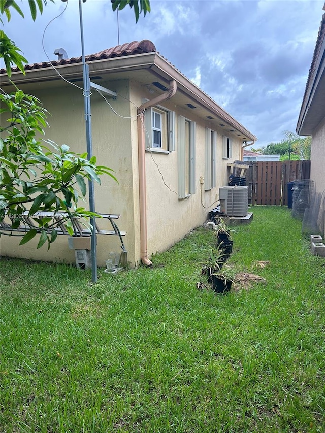 view of side of home with central AC unit and a yard